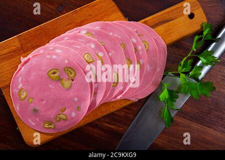 Appetitliche italienische Wurst Mortadella mit Oliven dünn auf Holztisch geschnitten Stockfoto