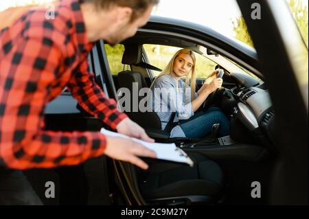Frau im Auto schaut auf Lehrer mit Checkliste Stockfoto
