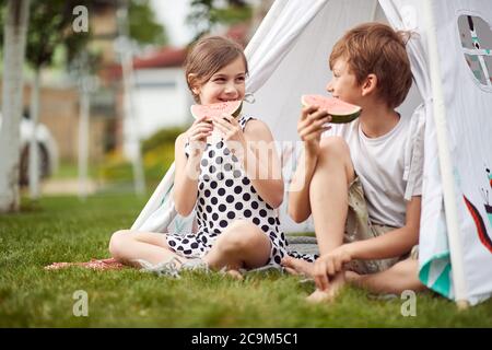 Junge Jungen und Mädchen genießen Wassermelone in einem Camp an einem heißen Tag Stockfoto