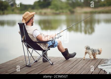 Ein Mann, der mit seinem Hund auf einem Dock angeln kann Stockfoto