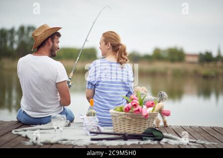 Glückliche Ehegatten genießen Angeln und ein Picknick mit ihrem Hund bei schönem Wetter Stockfoto