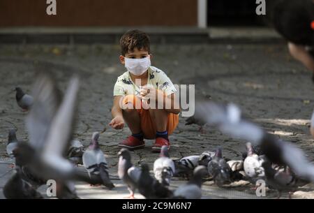 (200801) -- PEKING, 1. August 2020 (Xinhua) -- EIN Junge mit Gesichtsmaske füttert Tauben in Ankara, Türkei, 17. Juli 2020. (Foto von Mustafa Kaya/Xinhua) Stockfoto