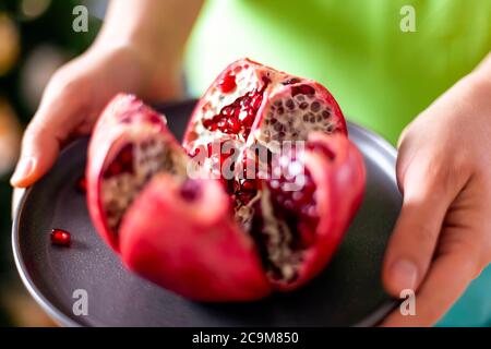 Frau Hände mit Granatapfel Obst auf grauem Teller. Nahaufnahme Stockfoto