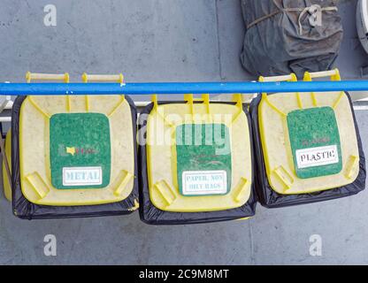 Drei gelbe Mülltonnen für die Mülltrennung auf dem Deck eines Schiffes in der Nordsee, von oben gesehen. Stockfoto