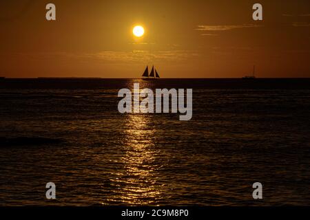 Segelboot auf dem Meer bei Sonnenuntergang. Yacht vor Sonnenaufgang Hintergrund. Wunderschöner Sonnenuntergang über dem Meer mit Bootssegeln. Stockfoto