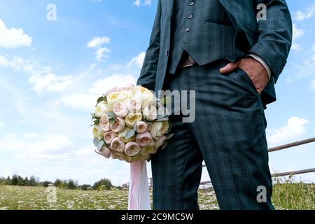 Ein Mann in einem stilvollen Anzug mit einem Blumenstrauß in der Hand Stockfoto