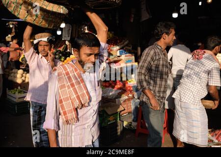 Porters in Crawford Market (Mahatma Jyotiba Phule Market), ein Großhandelsmarkt für Obst in Mumbai, Indien, balanciert seinen Korb über den Kopf Stockfoto