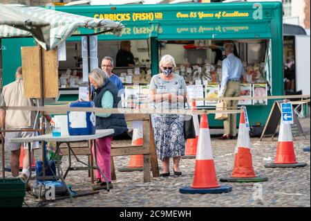 Richmond, North Yorkshire, UK - 1. August 2020: Reife Frau wartet in der Schlange mit einer schützenden Gesichtsmaske auf einem Outdoor-Markt Stockfoto