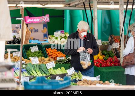 Richmond, North Yorkshire, Großbritannien - 1. August 2020: Ein reifer Mann mit einer schützenden Gesichtsmaske führt Einkäufe an einem Obst- und Gemüsemarkt im Freien Stockfoto