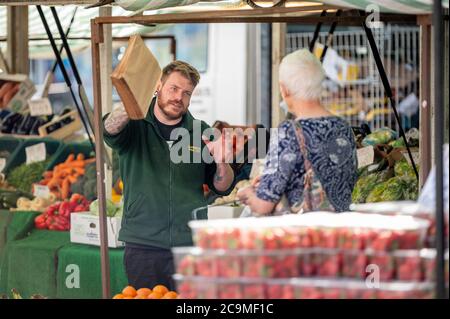 Richmond, North Yorkshire, Großbritannien - 1. August 2020: Ein Marktstandsbesitzer im Freien, der mit einer reifen Kundin spricht Stockfoto