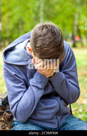 Trauriger junger Mann im Park versteckt sein Gesicht und weint Stockfoto