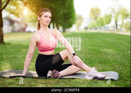 Frau streckt sitzende Wirbelsäulendrehung. Mädchen Yoga üben, tun halb herr der Fische Übung, Ardha Matsyendrasana Pose in der Stadt öffentlichen Park Stockfoto