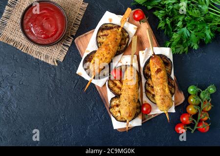 Lula Kebab mit gegrillter Aubergine auf Pita-Brot. Hähnchenkebab auf einem Spieß mit Gemüse auf dem schwarzen. Stockfoto