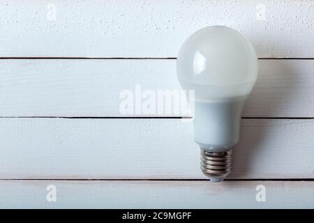 led-Lampe, eine wirtschaftliche Lampe liegt auf einem Holzhintergrund aus Brettern. Stockfoto