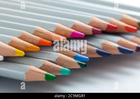 Mehrere Buntstifte, die aus einer Packung heraus auf dem Blatt Papier stehen. Stockfoto