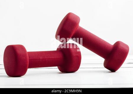 Kurzhanteln Gewicht für Fitness rot Farbe auf weißem Holzbrett. Stockfoto