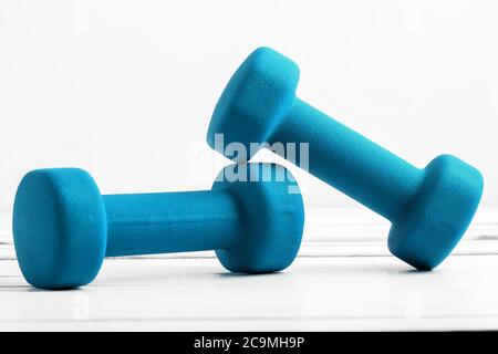 Kurzhanteln Gewicht für Fitness türkis Farbe auf weißem Holzbrett. Stockfoto