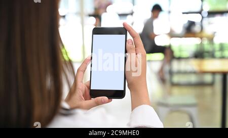 Zugeschnittenes Bild Frauen Hände sind mit einem weißen leeren Bildschirm Smartphone im Café. Stockfoto