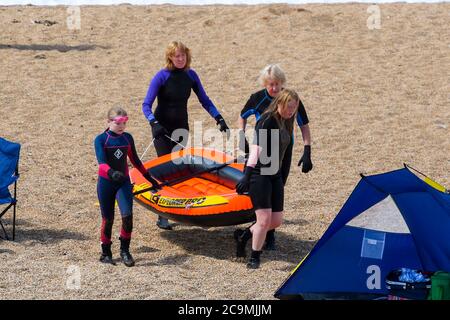 Burton Bradstock, Dorset, Großbritannien. August 2020. Wetter in Großbritannien. Urlauber tragen ein Schlauchboot am Freshwater Beach bei Burton Bradstock in Dorset an einem Tag voller heißer Sonneneinfälle. Bild: Graham Hunt/Alamy Live News Stockfoto