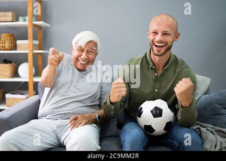 Opa und Enkel beobachten Fußball Sport Match im Fernsehen Stockfoto
