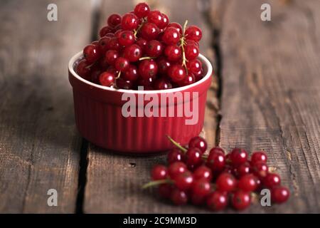 Rote Johannisbeeren in einer Schüssel auf einem Holzhintergrund Stockfoto