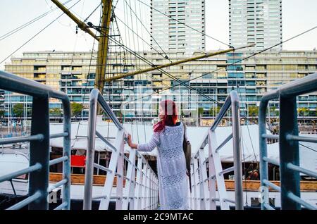 Eine rothaarige brasilianerin in ihren 20ern, die ein großes Boot betritt, das im Geschäftsviertel von Puerto Madero geparkt ist und zur Seite schaut und lächelt. Stockfoto