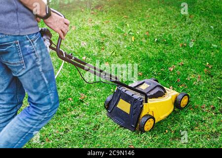 Mann, der einen Rasenmäher bewegt, um das Gras auf dem Rasen zu schneiden. Sonniger Herbsttag. Gartenarbeit Werkzeug. Fotos mit Bewegungsunschärfen und weichem Fokus. Leerer Ort Stockfoto