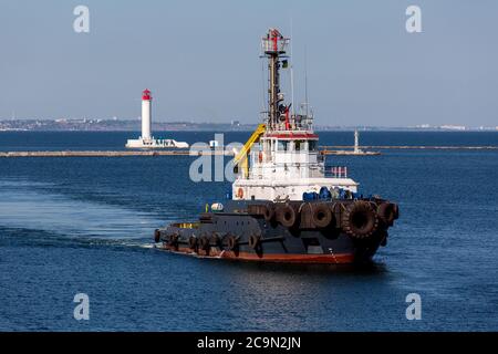 Schlepper mit Feuerwehrkoffer auf Manövern auf See, hinter Leuchtfeuer. Stockfoto