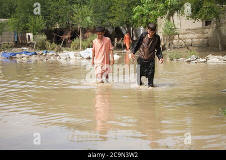 (200801) -- JALALABAD, 1. August 2020 (Xinhua) -- afghanische Kinder waten nach einer Sturzflut im Dorf Kalatak im Bezirk Kozkunar der Provinz Nangarhar, Afghanistan, 1. August 2020 durch das Flutwasser. Mindestens 16 Personen, hauptsächlich Kinder, wurden getötet, als die Sturzflut mehrere Häuser im Bezirk Kozkunar in der östlichen Provinz Nangarhar am späten Freitagabend wegspülte, sagte der Sprecher der Provinzregierung Attaullah Khogiani am Samstag. (Foto von Saifurahman Safi/Xinhua) Stockfoto