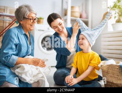 Oma, Mutter und Kind machen Wäsche zu Hause. Drei Generationen Familie Stockfoto