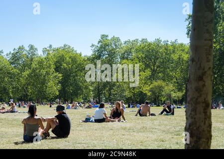 Menschen, die sich an einem sonnigen Tag in einem Park sozial distanzieren Stockfoto