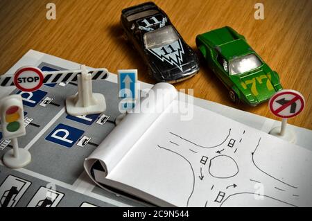 Notepad, Buch der Regeln, Spielzeugautos, Ampeln und Zeichen auf einem Schreibtisch Tisch Anschlag. Studium und der Vorbereitung auf die Fahrprüfung Stockfoto