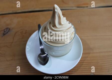 Goat's Milk Soft Serve Eis in einem Glas Dessertgericht, mit einem silbernen Löffel Stockfoto