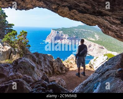 Wanderer mit Rucksack durch eine Höhle in Capo Caccia. Sardinien, Italien Stockfoto