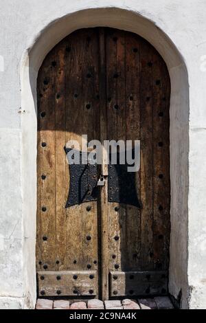 Antike Holztür mit geschmiedetem Griff und Vorhängeschloss im historischen Gebäude aus weißem Kalkstein Stockfoto