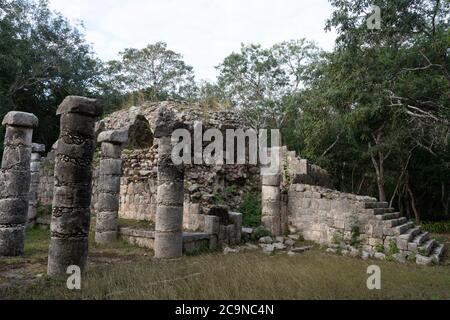 Steinsäulen der Westkolonnade auf dem Platz der tausend Säulen mit einem ruinierten Gebäude in den Ruinen der großen Maya-Stadt Chichen Itza. Stockfoto