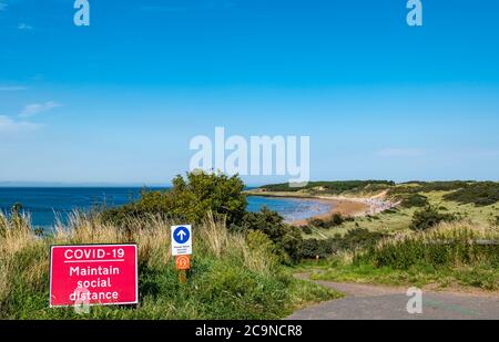 Überfüllter Strand mit sozialer Distanz und Einbahnschildern am heißen Sommertag während der Covid-19 Pandemie, Gullane, East Lothian, Schottland, Großbritannien Stockfoto