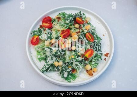 Caesar Salat in der weißen Dishe auf dem weißen Tisch. Stockfoto