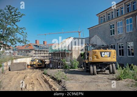 Elstal, Deutschland. Juli 2020. Baufahrzeuge stehen auf dem Gelände des Olympischen Dorfes im brandenburgischen Elstal. Seit Januar 2019 saniert der Nürnberger Immobilienentwickler terraplan das denkmalgeschützte Speisehaus der Nationen inklusive des ehemaligen Kesselhauses, dem zukünftigen Haus Central. Darüber hinaus werden weitere neue Wohngebäude rund um diese Gebäude errichtet. Insgesamt werden in der ersten Bauphase bis 2022 rund 365 Wohnungen gebaut. Quelle: Paul Zinken/dpa-Zentralbild/ZB/dpa/Alamy Live News Stockfoto