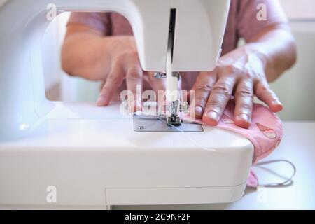 Mann Hände nähen eine medizinische Gesichtsmaske an einer Nähmaschine. Do it yourself, Zero Waste und Coronavirus Konzepte. Stockfoto