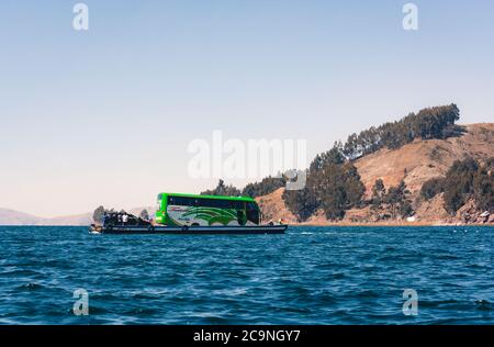 SAN PEDRO DE TIQUINA, BOLIVIEN - 23. JULI 2016: Ein Touristenbus wird auf einem Holzfloß im Titicacasee, Bolivien, gefahren Stockfoto