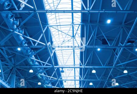 Blaue Lichter und Lüftungssystem in einer langen Linie an der Decke des Industriegebäudes. Ausstellungshalle. Deckenkonstruktion Stockfoto