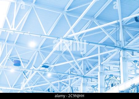 Blaue Lichter und Lüftungssystem in einer langen Linie an der Decke des Industriegebäudes. Ausstellungshalle. Deckenkonstruktion Stockfoto