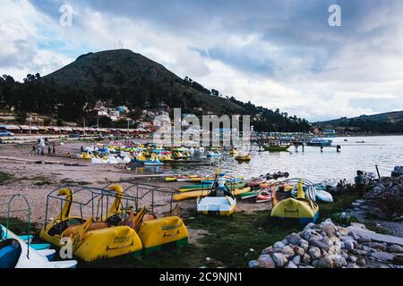 Landschaft von Copacabana an der Küste des Titicaca-Sees, mit bunten Fußpedalbooten und einem grünen Berg in Stockfoto