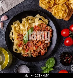 Traditionelle italienische Pasta Bolognese auf schwarzem Teller, Draufsicht. Stockfoto