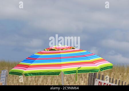 Ein farbenfroher Sonnenschirm neben einer Düne in Lavallette, New Jersey, USA Stockfoto