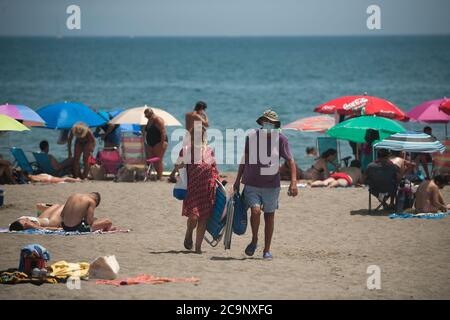 Malaga, Spanien. August 2020. Ein Paar mit Gesichtsmasken gesehen verlassen Rincon Sol Strand von Torremolinos während eines heißen Sommertages.die erste schwere Hitzewelle trifft das Land mit hohen Temperaturen. In Andalusien sind laut der spanischen Meteorologischen Agentur die meisten Städte in orangefarbener Warnung mit Temperaturen über 40 Grad Celsius am Wochenende. Kredit: Jesus Merida/SOPA Images/ZUMA Wire/Alamy Live Nachrichten Stockfoto