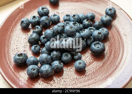 Frische Brombeeren oder Blaubeeren in einer braunen Tontafel, fotografiert von oben. Nahaufnahme von frischen, gesunden Sommerbeeren. Stockfoto