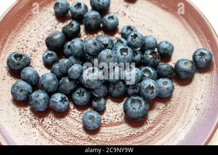 Frische Brombeeren oder Blaubeeren in einer braunen Tontafel, fotografiert von oben. Nahaufnahme von frischen, gesunden Sommerbeeren. Stockfoto