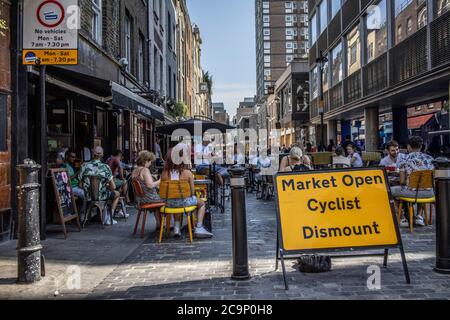 Die Leute sitzen draußen auf der Berwick Street und genießen die Café-Kultur an einem warmen Sommernachmittag, Post Coronavirus Lockdown, Soho, London, England, Großbritannien Stockfoto